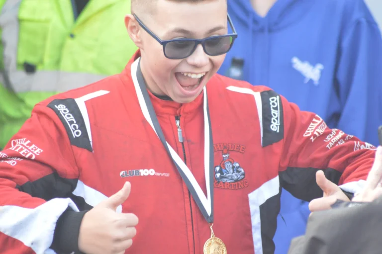 Samuel smiling and giving a thumbs up with his medal